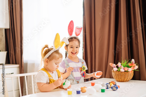 Little happy children draw Easter eggs in the kitchen. a little girl is laughing with an Easter egg in her hands. Easter holiday for children