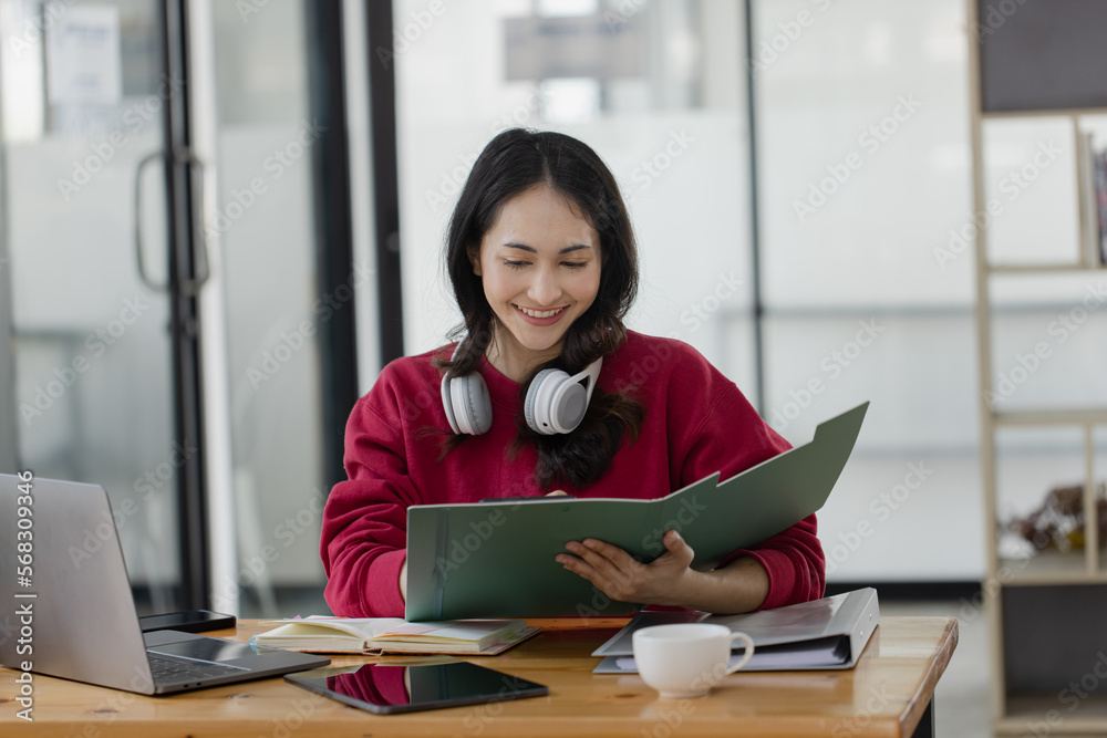 Happy smiling young asian business woman wear headphones working online sitting at desk in the office, Happy smiling young asian business woman wear headphones working online sitting at desk in the office,