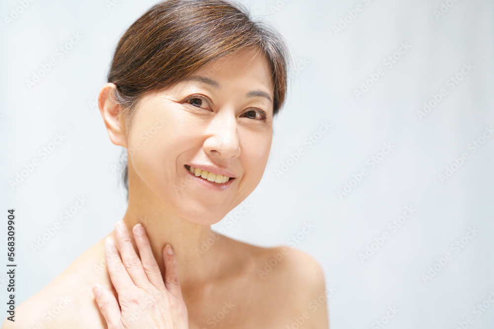 首元に手をやる笑顔の中年女性 首元に手をやる笑顔の中年女性
