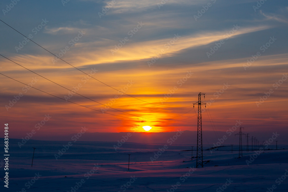 electrical wires at sunset on a snow-covered ground