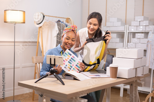 Two asian and african american woman business owner fashion designer cloth tailor creative working for new collection.Happy online store owner preparing an order for shipping .
