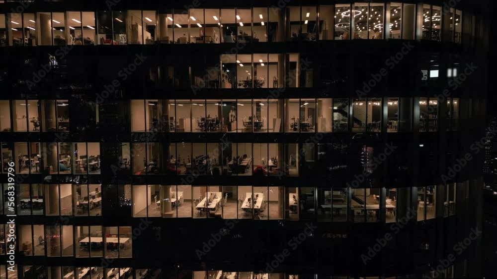 Stunning aerial view of an office building with illuminated empty offices shining bright at night close-up. Post-pandemic reality. Stunning aerial view of an office building with illuminated empty offices shining bright at night close-up. Post-pandemic reality.