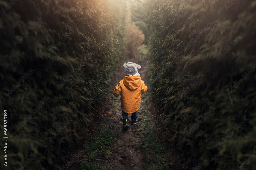 Small boy wearing winter yellow jacket and furry hat running be Small boy wearing winter yellow jacket and furry hat running be