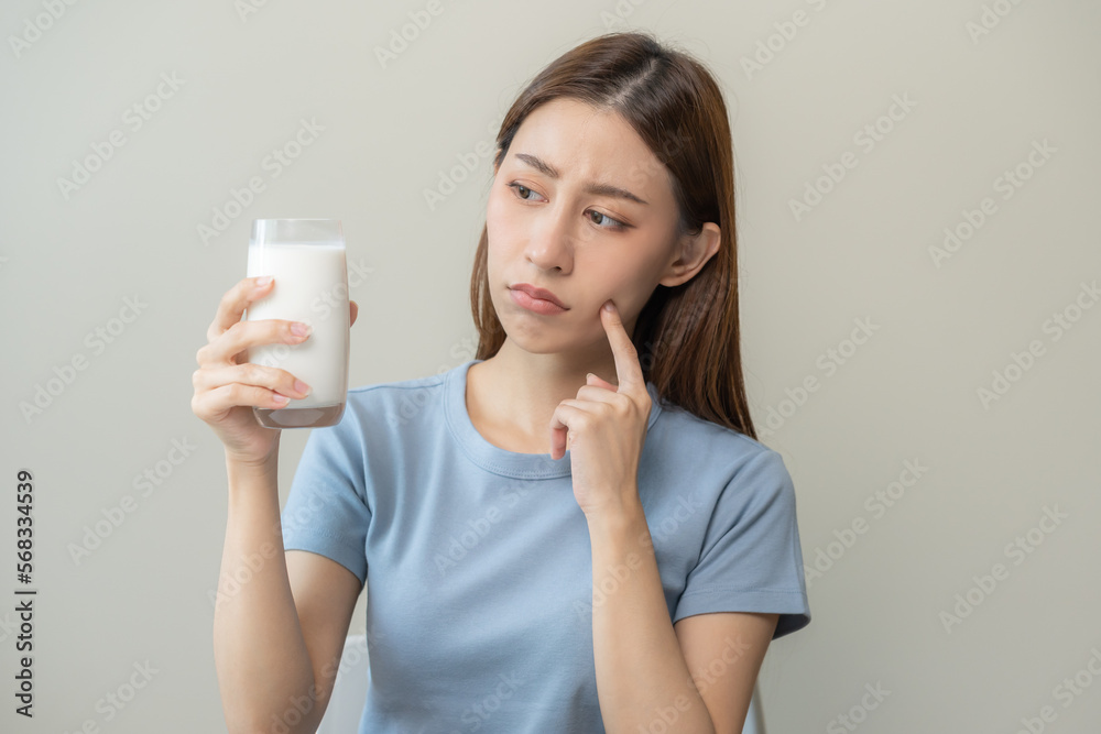 Allergy asian young woman, girl looking, holding glass of milk, face in