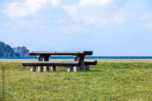 海辺の芝生に置かれた古びた木のベンチとテーブル