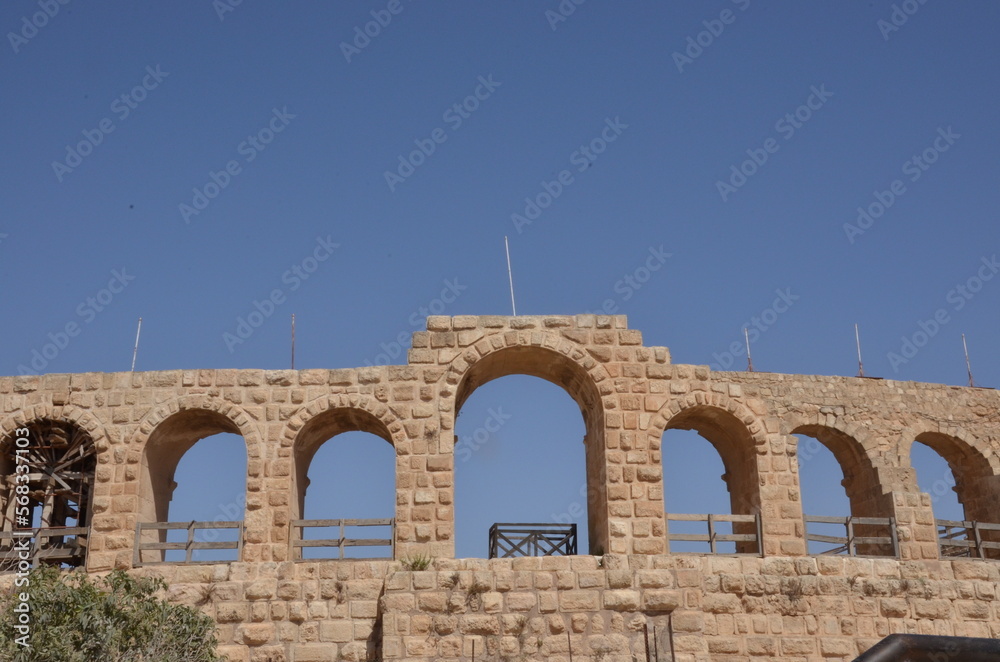Fototapeta premium Sunny temples, arches, the Nymphaeum, stone ornaments, columns and column bases on the ruins of the city of Jerash in Jordan.