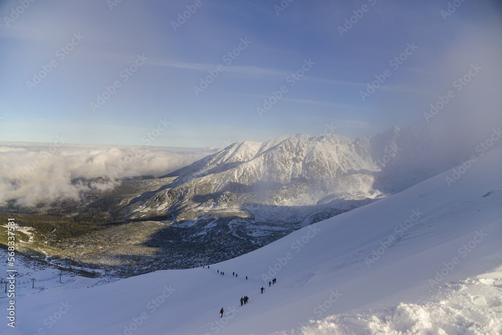 Obraz premium Climbing tourists in winter to the peak of a mountain peak