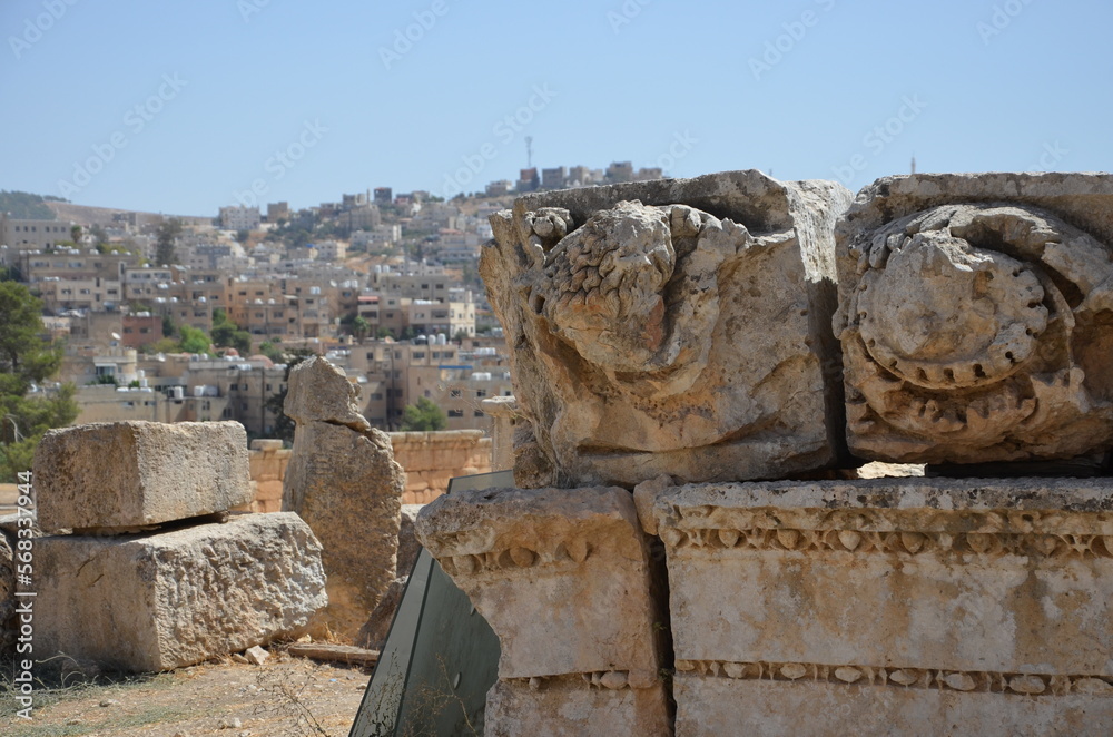 Sunny temples, arches, the Nymphaeum, stone ornaments, columns and column bases on the ruins of the city of Jerash in Jordan.