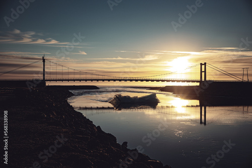 Iceland Jökulsárlón glacier lagoon lake floating ice floe under bridge with orange blue sunset