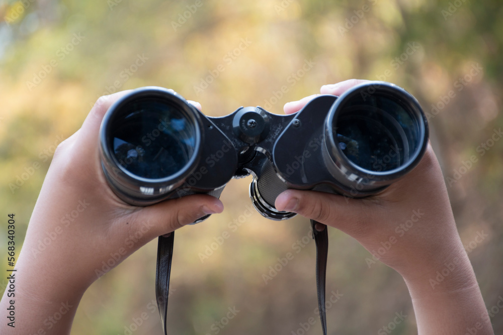 Closeup view of binoculars holding in hands of young asian natural surveyor, blurred dry autumn national forest park background. Closeup view of binoculars holding in hands of young asian natural surveyor, blurred dry autumn national forest park background.