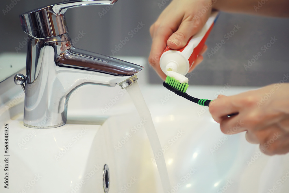 Hands with tooth brush and paste on blurred background in the bathroom ...