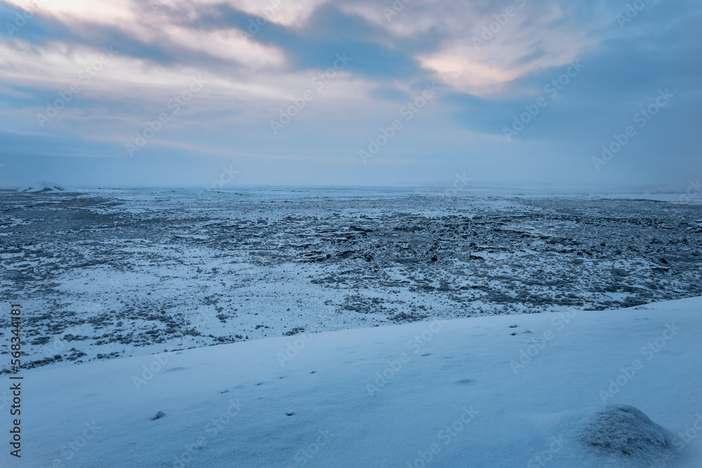 Iceland snow covered vulcanic area in winter with cloudy blue yellow sky