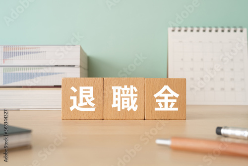 Fotografía 退職金と書かれたブロックが置かれたデスク