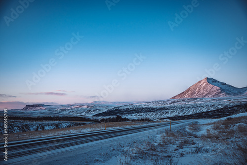 Iceland road with snow covered mountains in winter sunset with blue sky