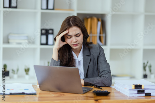 Young businesswoman are stressed and tired from work sitting at desk in the office, feeling sick at work, stress from work.  © SOMKID