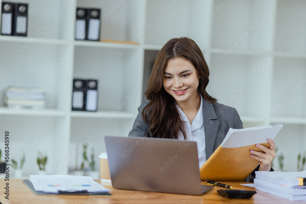 Businesswoman working with laptop and document paper sitting at desk in office workplace, business finance and accounting, business online training concept. Businesswoman working with laptop and document paper sitting at desk in office workplace, business finance and accounting, business online training concept.