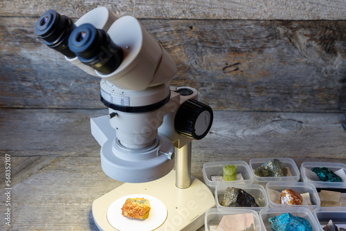 木のテーブルの上に置いた顕微鏡を使って鉱物を調べる