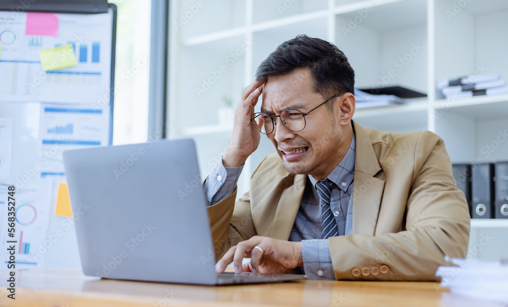 Stressed and sad Asian man sitting at desk in office, freelance business, Asian man emotion feelings, sad upset face. Stressed and sad Asian man sitting at desk in office, freelance business, Asian man emotion feelings, sad upset face.
