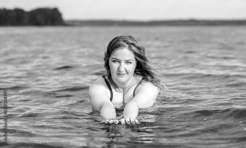Fototapeta premium Plus size woman in water in swimsuit. Chubby nice lady, body positive concept, different women sizes