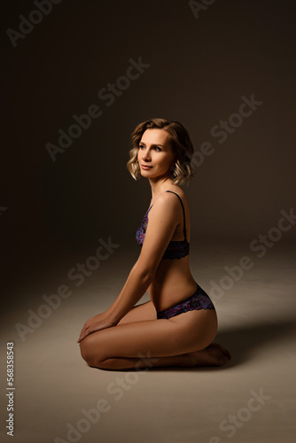 Beautiful slim young woman in lingerie on a dark background in a photo studio © Olga