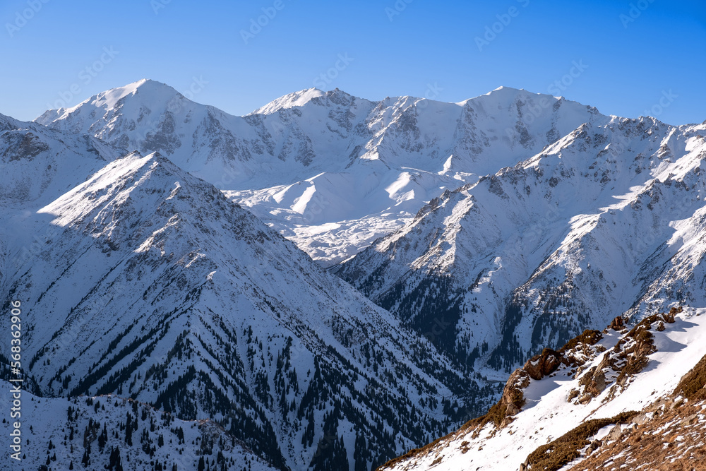 Snow-covered mountain peaks after a recent snowfall; majestic mountain ranges against the blue sky in the winter season