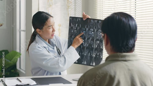 Young Asian woman doctor showing lung x-ray test results and describe to a senior patient in hospital. For cancer awareness month