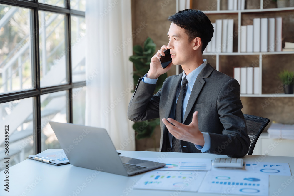 Asian young freelancer working from home remotely.He is talking on the phone.