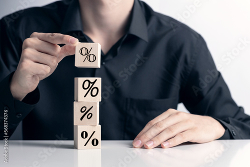 %, compound interest, debt, inflation concept, rising interest rates, Hand building a tower from wooden cubes with percent symbol