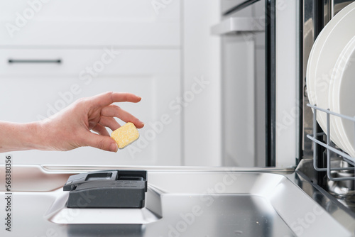 woman loading tablet into dishwasher with plates, closeup
