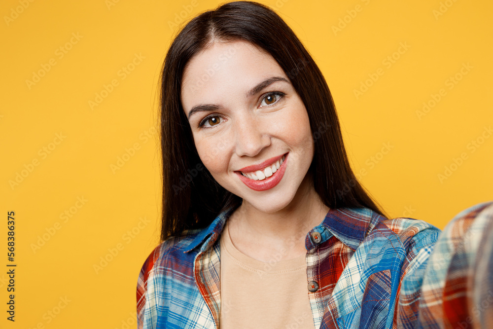 Close up young cheerful smiling caucasian woman wear blue shirt beige t-shirt doing selfie shot pov on mobile cell phone isolated on plain yellow background studio portrait. People lifestyle concept. Close up young cheerful smiling caucasian woman wear blue shirt beige t-shirt doing selfie shot pov on mobile cell phone isolated on plain yellow background studio portrait. People lifestyle concept.