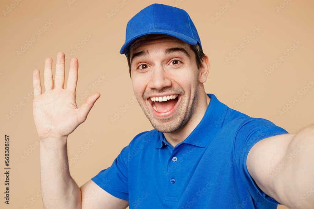 Close up delivery guy employee man wear blue cap t-shirt uniform workwear work as dealer courier do selfie shot pov on mobile cell phone waving hand isolated on plain beige background Service concept