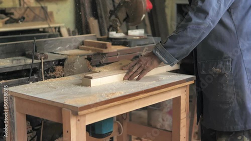 Slow motion. A professional carpenter working with wood on a woodworking machine grinds and polishes wood. Handmade furniture. Manufactures furniture parts in natural light. Carpentry tools
