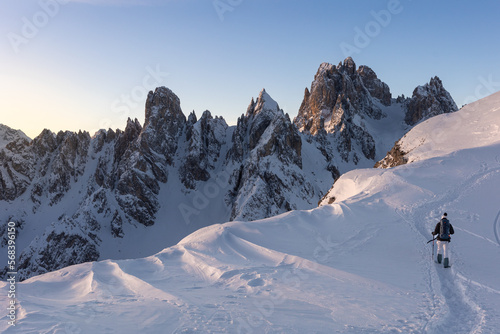 Photography hiker walking a trail in dolomites mountains during winter with a lot of snow
