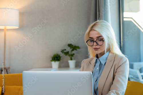 Young businesswoman in glasses working on laptop or computer in office. Female student trainee photo