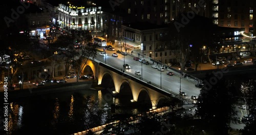 Intense night traffic on the brightly lit Saarbruecken Bridge across the Kura River in Tbilisi, the capital of Georgia. The concept of tourist attractions of the Georgian capital city of Tbilisi. photo