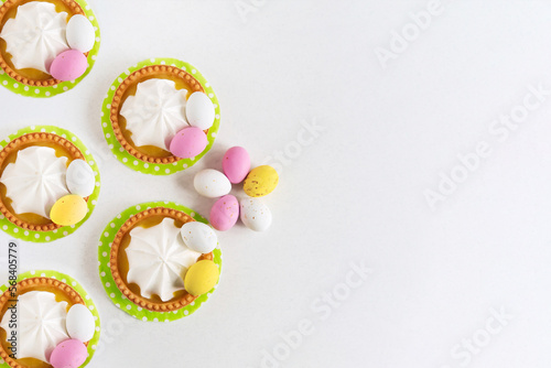 Five Easter tartlets decorated with sweets Easter eggs on a light background, close-up. Copy space. Easter delicious dessert.