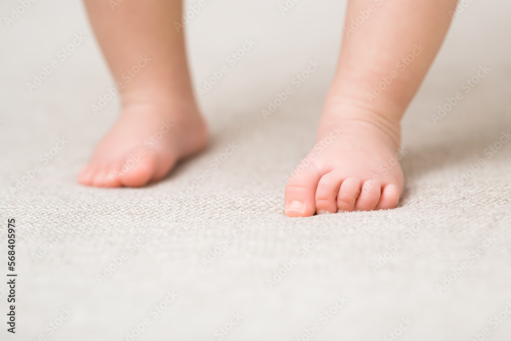 Baby barefoot on light soft сarpet. Closeup. First steps. Front view. Baby barefoot on light soft сarpet. Closeup. First steps. Front view.