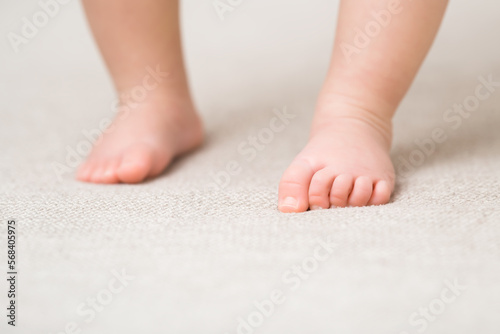 Baby barefoot on light soft сarpet. Closeup. First steps. Front view. © fotoduets