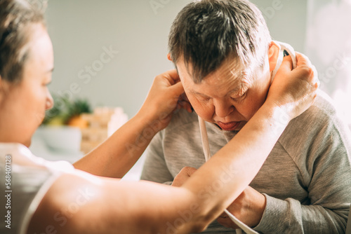 elderly woman with Down syndrome accompanied by an assistantto help her, asian woman