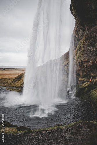 Landscape of a waterfall in Iceland seen from the side with a breathtaking meadow in front