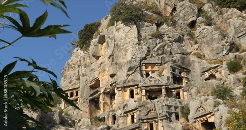 Ruins of ancient Lycian tombs carved into the rock on territory of the city of Demre Mira Limira in the Turkish province of Antalya. Concept of tourists visiting ancient cultural monuments photo