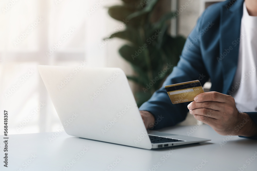 Person holding a credit card, uses a credit card to pay for goods and services online, the concept of using a credit card for online shopping, ordering goods and services on the website. Person holding a credit card, uses a credit card to pay for goods and services online, the concept of using a credit card for online shopping, ordering goods and services on the website.