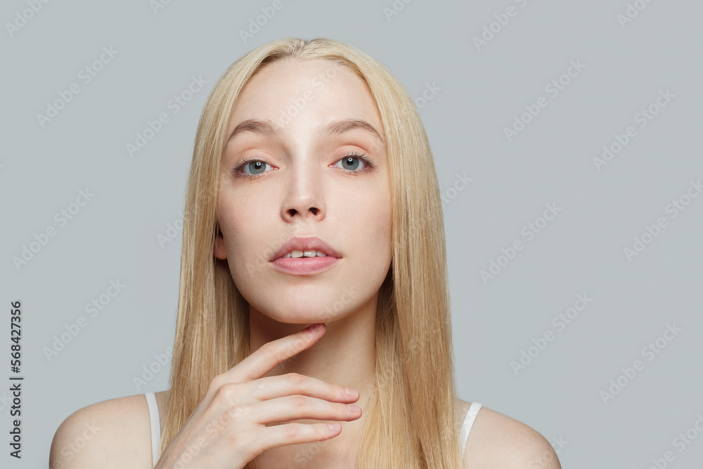 Pretty woman with blonde hair and hand isolated on grey background. Beauty, cosmetics, skincare, glamour Pretty woman with blonde hair and hand isolated on grey background. Beauty, cosmetics, skincare, glamour