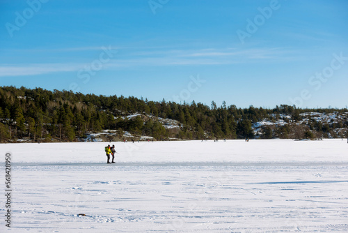 A couple of people ice skating on a frozen lake in Sweden on sunny day