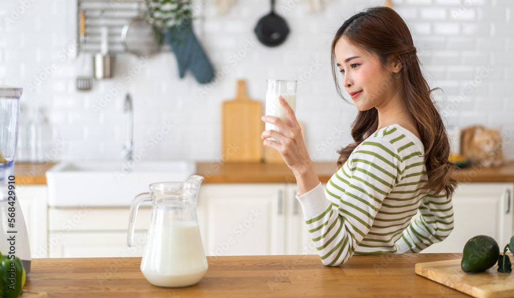 Portrait of beauty healthy asian woman smiling and having protein breakfast drinking and hold glasses of milk on counter in kitchen at home.Diet concept.healthy drink Portrait of beauty healthy asian woman smiling and having protein breakfast drinking and hold glasses of milk on counter in kitchen at home.Diet concept.healthy drink
