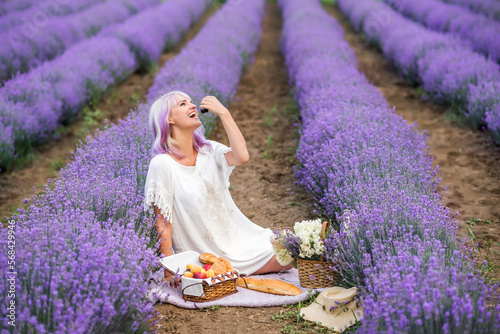 young woman is sitting in lavender flowers. Picnic on the field