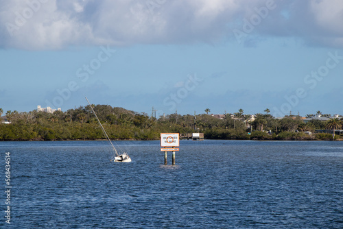 Sunken boat beside a caution shoal area sign