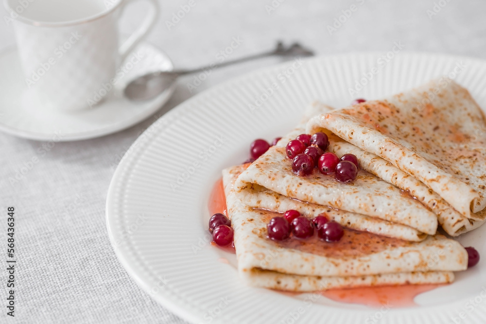 Russian traditions. Russian holiday Maslenitsa. Still life with a cup of tea, a stack of pancakes with northern cranberries, cubes of butter on the table. Russian traditions. Russian holiday Maslenitsa. Still life with a cup of tea, a stack of pancakes with northern cranberries, cubes of butter on the table.