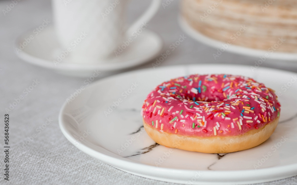 Delicious dessert. Pink donut with multicolored sprinkles, a cup of black coffee or tea. Sweets.