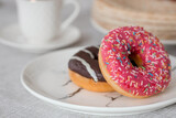 Delicious dessert. Pink and chocolate donut, with multicolored sprinkles, a cup of black coffee or tea. Sweets.